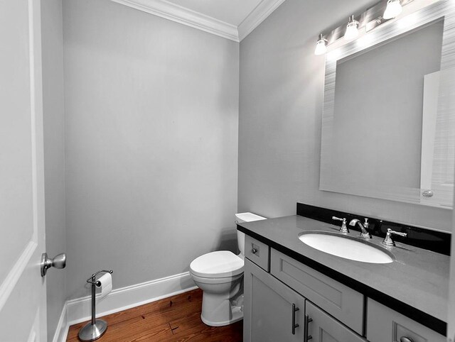 bathroom featuring vanity, toilet, wood-type flooring, and ornamental molding