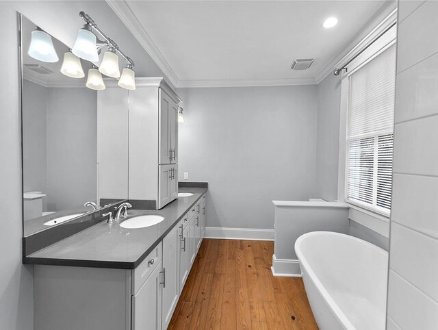 bathroom featuring a bathing tub, vanity, wood-type flooring, and crown molding