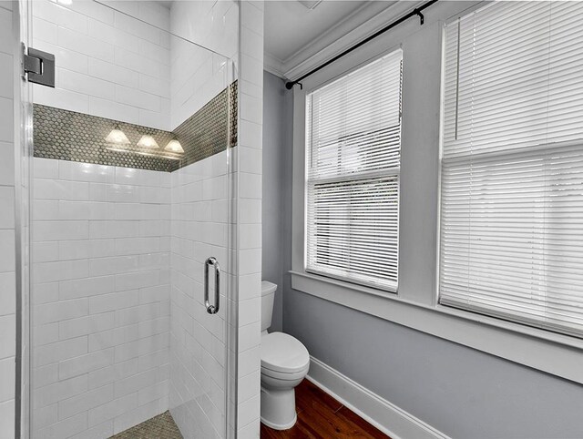 bathroom featuring toilet, a shower with door, wood-type flooring, and ornamental molding