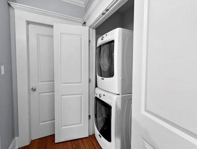 laundry area featuring dark wood-type flooring and stacked washer / drying machine