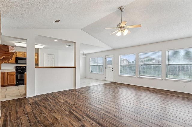 unfurnished living room with lofted ceiling, hardwood / wood-style flooring, ceiling fan, and a textured ceiling