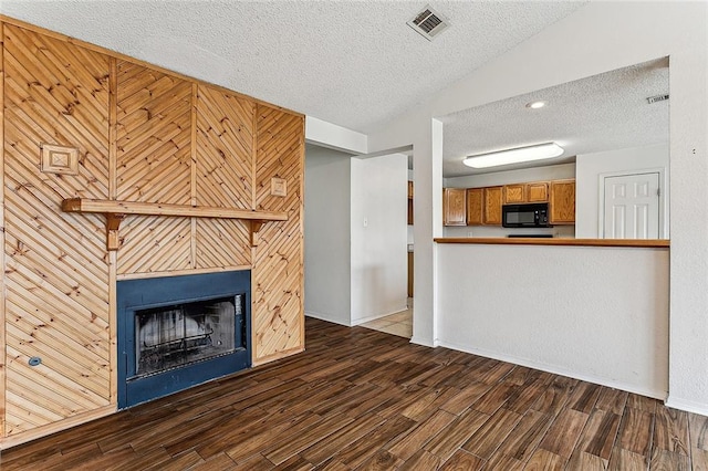 unfurnished living room featuring a textured ceiling, wood walls, dark hardwood / wood-style flooring, and a fireplace