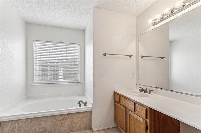 bathroom with a textured ceiling, vanity, and a relaxing tiled tub