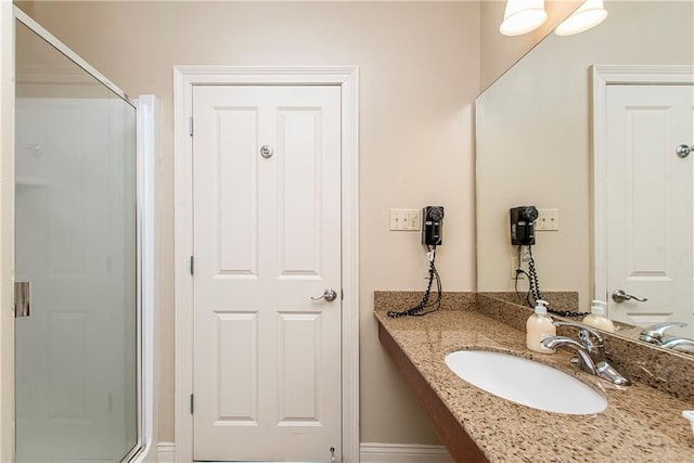 bathroom featuring a shower with door and vanity