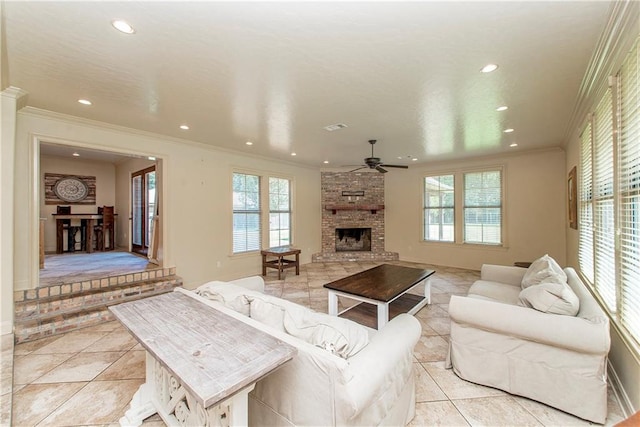 tiled living room with ornamental molding, ceiling fan, and a large fireplace