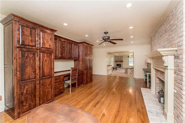 home office with ceiling fan, a fireplace, light hardwood / wood-style floors, and ornamental molding