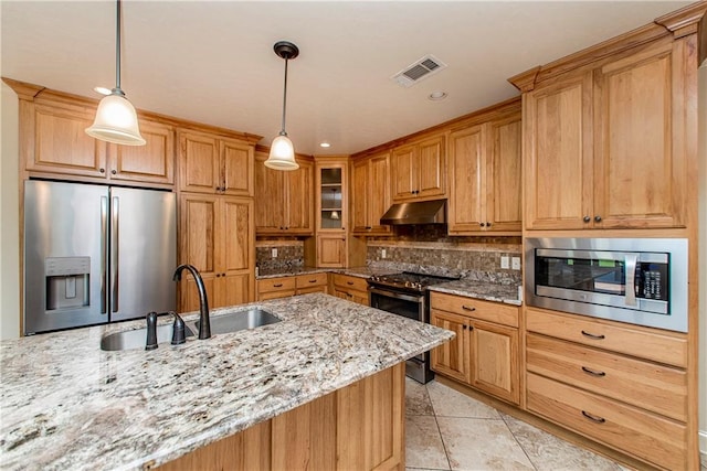 kitchen with light stone countertops, stainless steel appliances, pendant lighting, and sink