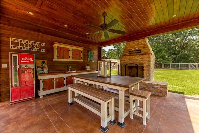 view of patio / terrace featuring an outdoor brick fireplace, ceiling fan, and a wet bar