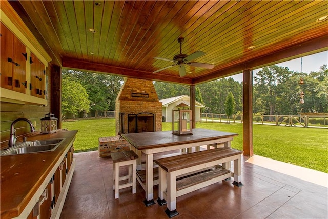 view of patio / terrace with ceiling fan, an outdoor brick fireplace, and sink