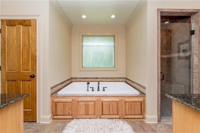 full bathroom featuring a bath, a stall shower, crown molding, and baseboards