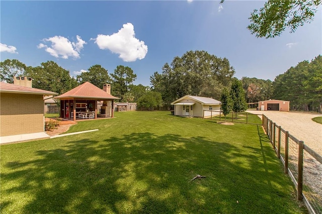 view of yard featuring a garage, an outbuilding, and fence