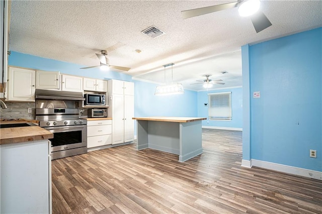 kitchen featuring pendant lighting, white cabinetry, butcher block counters, stainless steel appliances, and tasteful backsplash