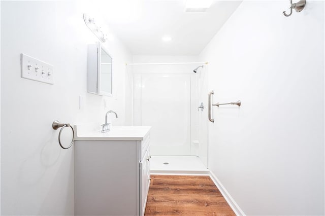 bathroom with a shower, hardwood / wood-style floors, and vanity