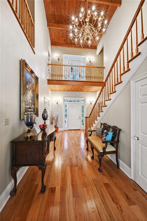 entryway with wooden ceiling, a towering ceiling, a chandelier, and hardwood / wood-style flooring