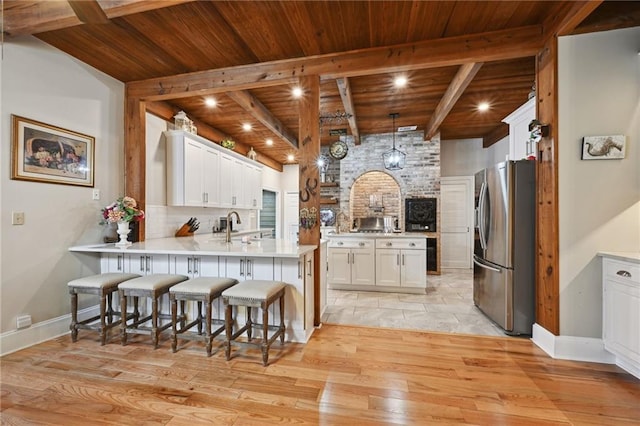 kitchen with white cabinets, wooden ceiling, light hardwood / wood-style flooring, a kitchen breakfast bar, and stainless steel fridge with ice dispenser