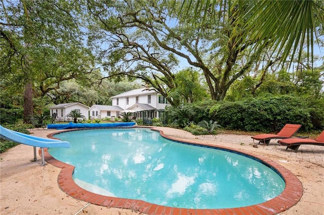 view of swimming pool featuring a water slide and a patio area