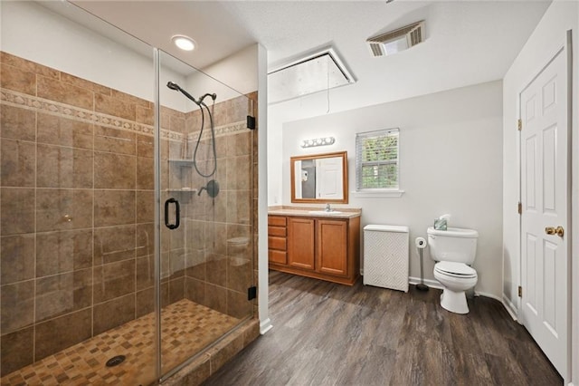 bathroom with toilet, an enclosed shower, wood-type flooring, and vanity