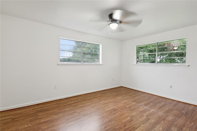 empty room with ceiling fan, wood-type flooring, and a healthy amount of sunlight