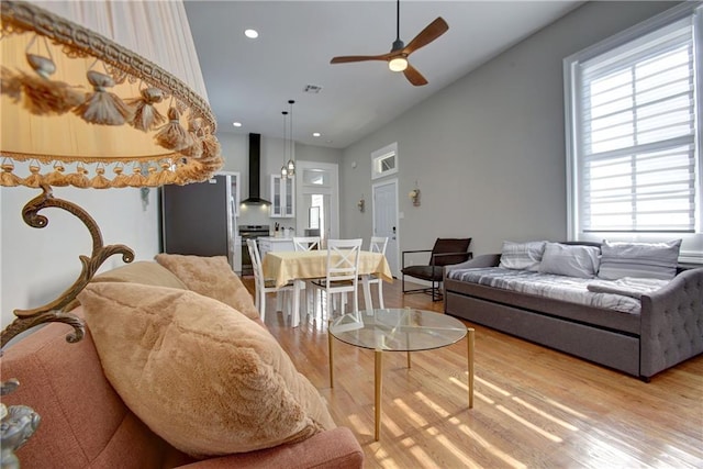 living room with a healthy amount of sunlight, ceiling fan, and light hardwood / wood-style flooring