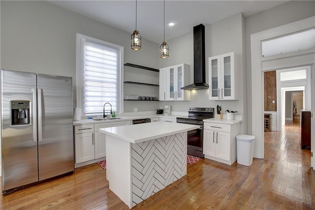 kitchen with a center island, light wood-type flooring, stainless steel appliances, white cabinetry, and wall chimney range hood