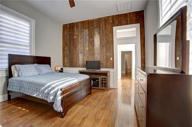 bedroom featuring ceiling fan, light wood-type flooring, and multiple windows