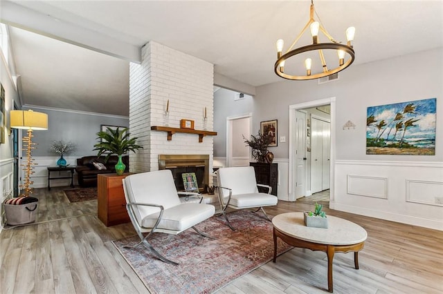 living area with an inviting chandelier, hardwood / wood-style floors, and a fireplace