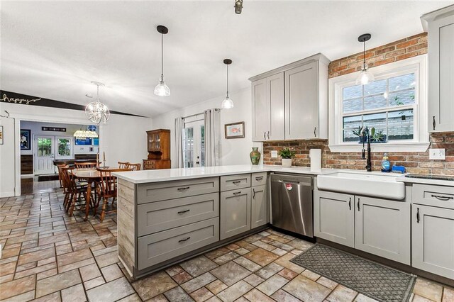 kitchen with hanging light fixtures, sink, stainless steel dishwasher, and kitchen peninsula