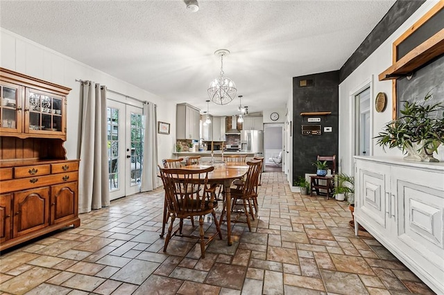 dining area featuring french doors, an inviting chandelier, and a textured ceiling