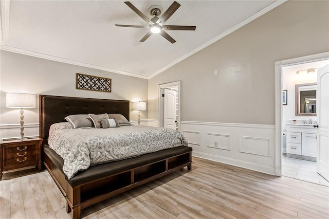 bedroom with light hardwood / wood-style flooring, ceiling fan, ensuite bathroom, ornamental molding, and vaulted ceiling