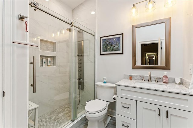 bathroom with vanity, toilet, and a shower with door