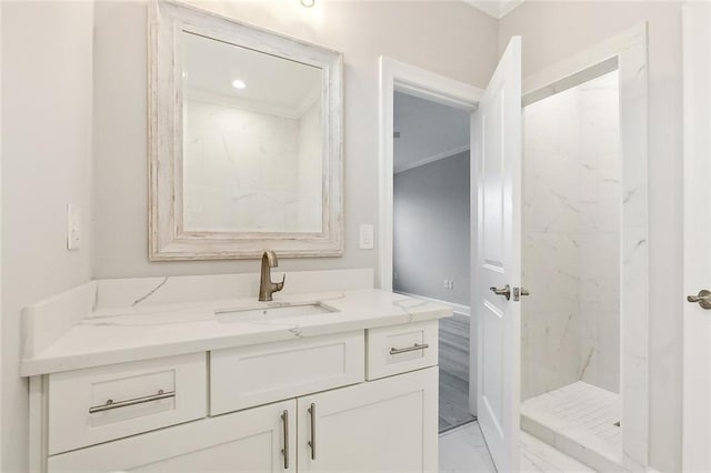 bathroom with ornamental molding, tiled shower, and vanity