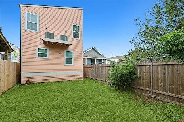 rear view of property with a yard and central AC unit