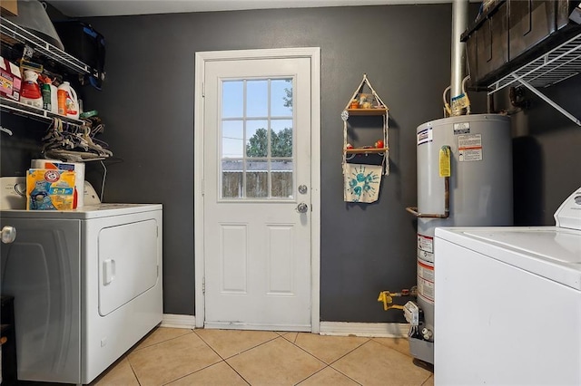 clothes washing area with light tile patterned floors, water heater, and separate washer and dryer