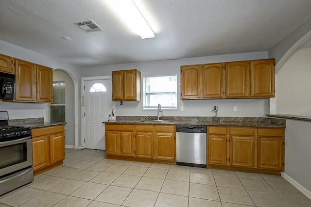 kitchen with appliances with stainless steel finishes, sink, and light tile patterned floors