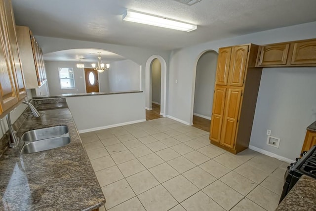 kitchen featuring light tile patterned flooring, a notable chandelier, hanging light fixtures, and sink