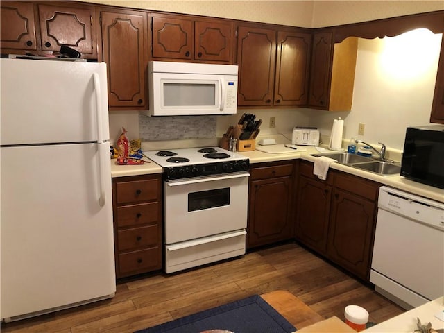 kitchen featuring dark wood-type flooring, white appliances, and sink