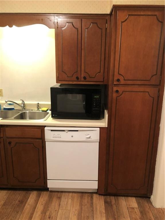 kitchen with white dishwasher, light hardwood / wood-style flooring, and sink