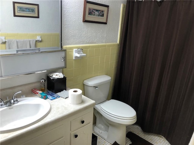 bathroom featuring tile patterned flooring, tile walls, toilet, and vanity