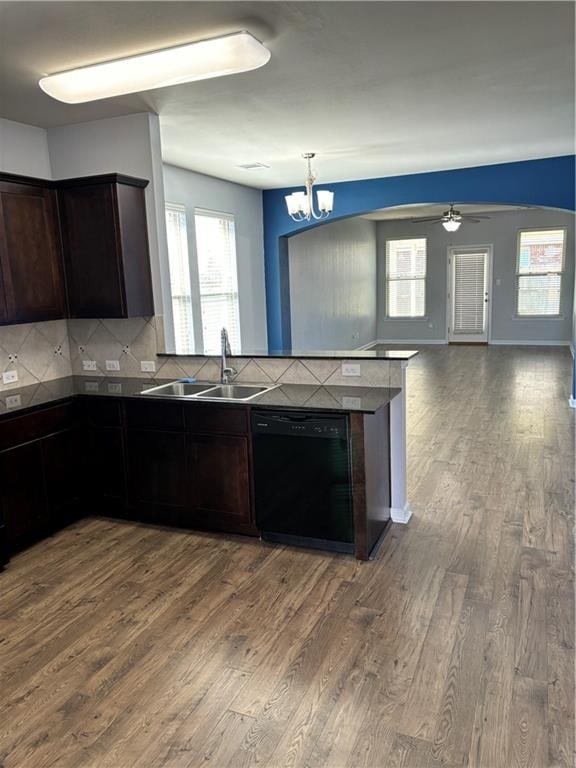 kitchen featuring wood-type flooring, black dishwasher, ceiling fan with notable chandelier, and backsplash