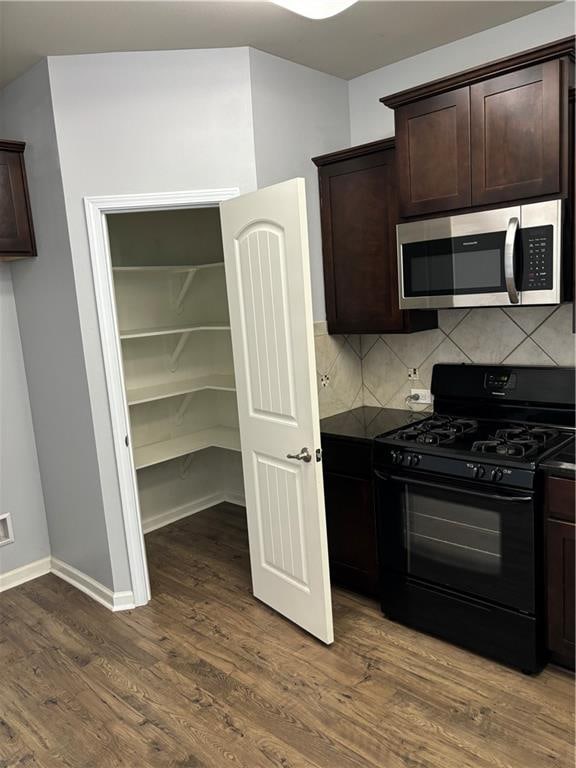 kitchen with black gas range, dark brown cabinetry, dark hardwood / wood-style flooring, and decorative backsplash