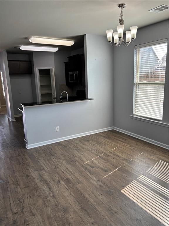 spare room featuring an inviting chandelier, dark wood-type flooring, and sink