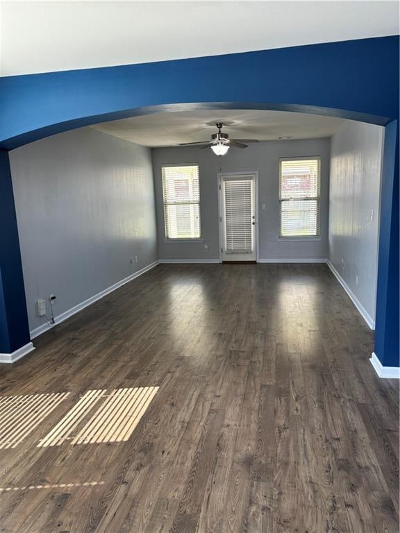 unfurnished living room featuring dark hardwood / wood-style flooring, ceiling fan, and plenty of natural light