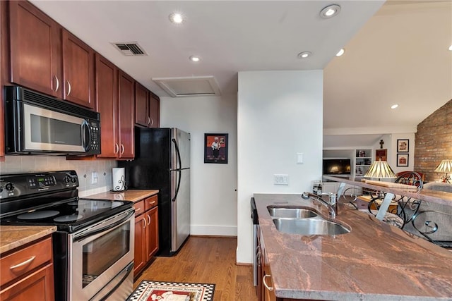 kitchen with backsplash, light hardwood / wood-style floors, sink, dark stone counters, and stainless steel range with electric cooktop