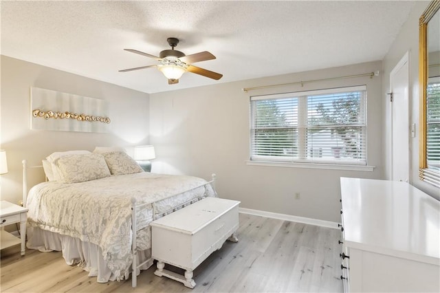 bedroom with a textured ceiling, ceiling fan, and light wood-type flooring