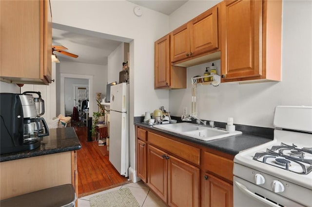 kitchen featuring white appliances, light hardwood / wood-style floors, ceiling fan, and sink