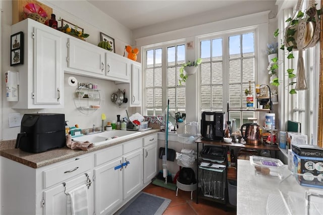 kitchen featuring dark tile patterned floors, white cabinets, and sink