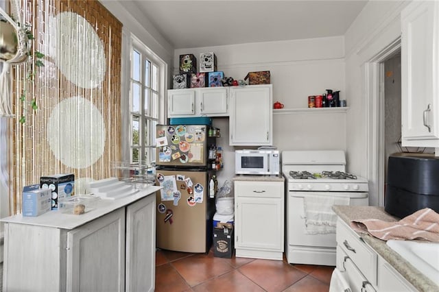 kitchen featuring dark tile patterned flooring, white appliances, and white cabinetry