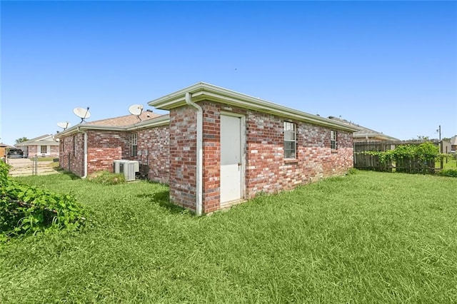 view of side of property with central air condition unit and a lawn