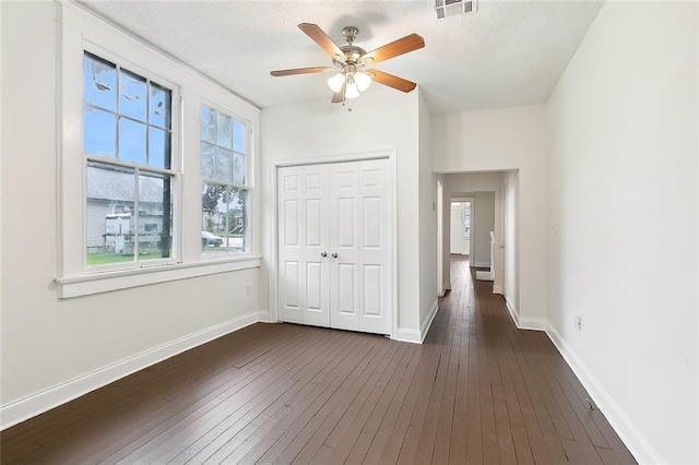 unfurnished bedroom featuring a closet, a textured ceiling, ceiling fan, and dark hardwood / wood-style floors