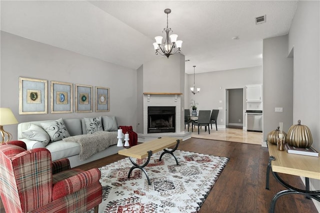 living room with a fireplace, dark hardwood / wood-style floors, a chandelier, and vaulted ceiling